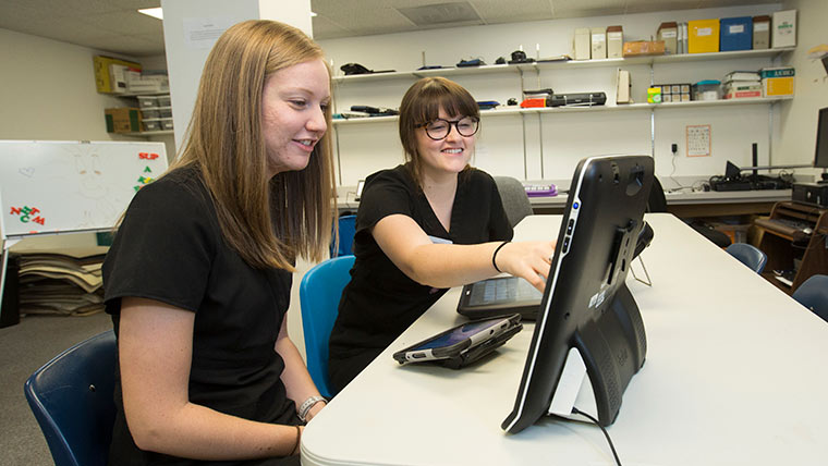 Two speech-language students looking at computer data together.