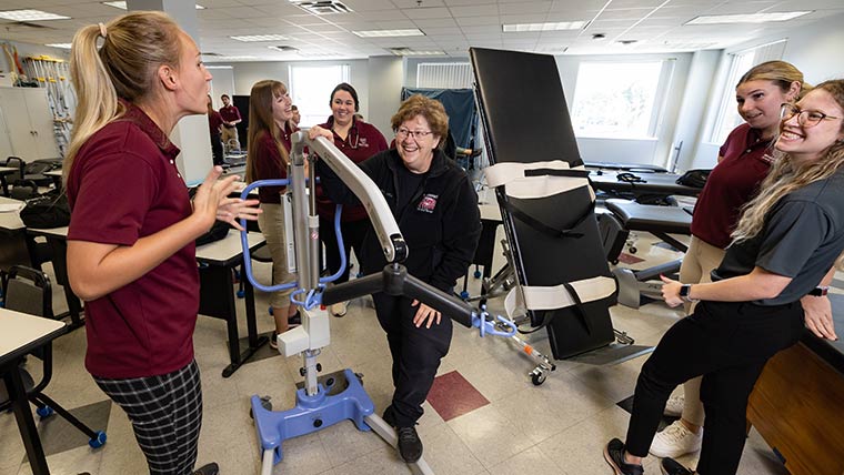 Physical therapy professor and a group of students sharing a laugh.