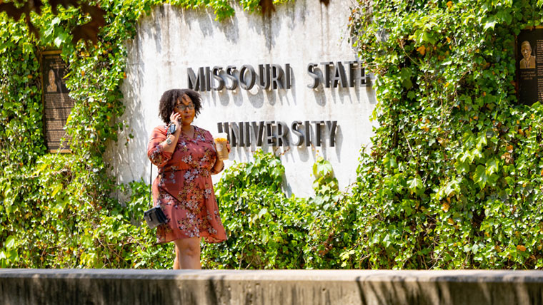 Student walking by the Missouri State University Wall