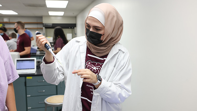 Student examining substance in syringe during class.