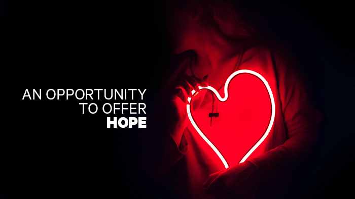Woman holding a neon heart, caption: "an opportunity to offer hope."