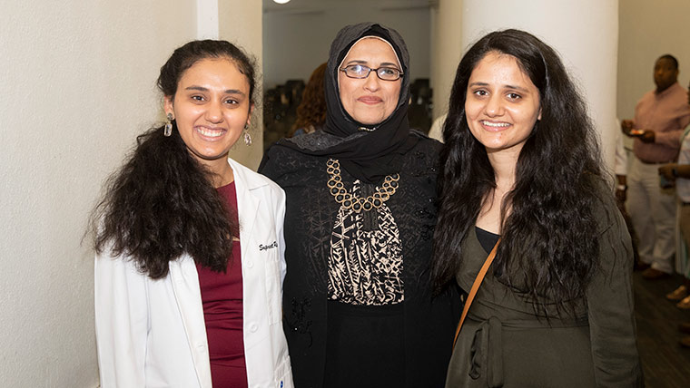 Audiology professor with two students at the program's white coat ceremony.