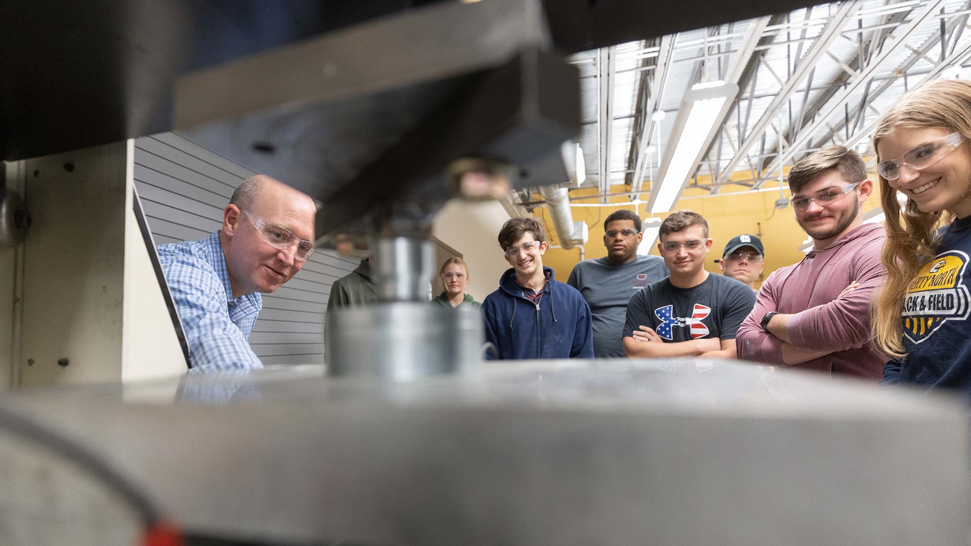 Dr. Matt Pierson and students watching a machine test concrete during a lab class.
