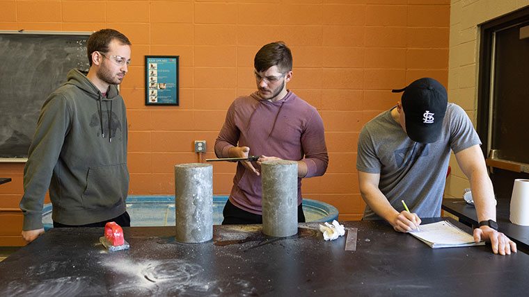 Three students preparing to do stress testing on a concrete block.
