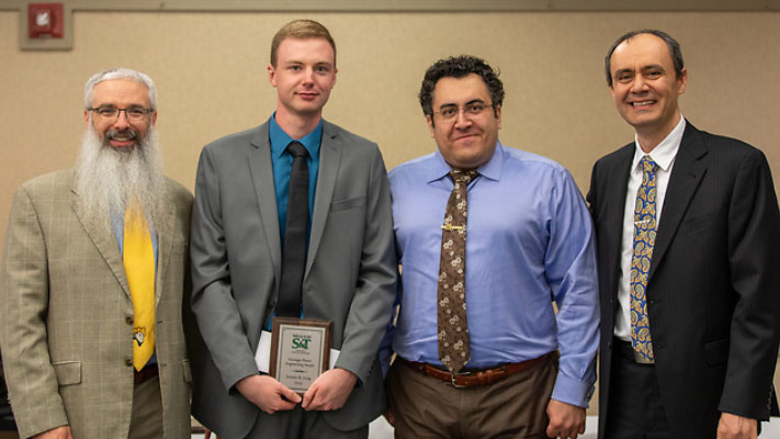 An electrical engineering student receiving the Grainger Power Engineering Award. Standing with him are faculty and staff members.
