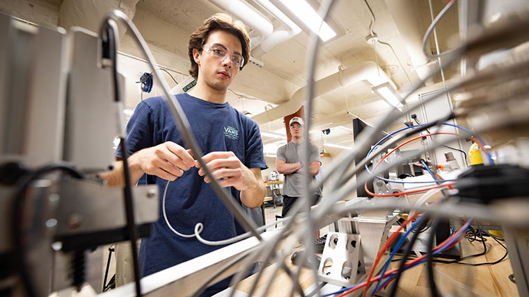 A student examines a series of wires and circuits.