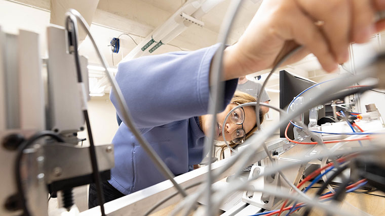 A mechanical engineering student connecting wires to a machine before they use it.