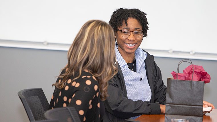 A business student smiling as she talks to a corporate mentor.