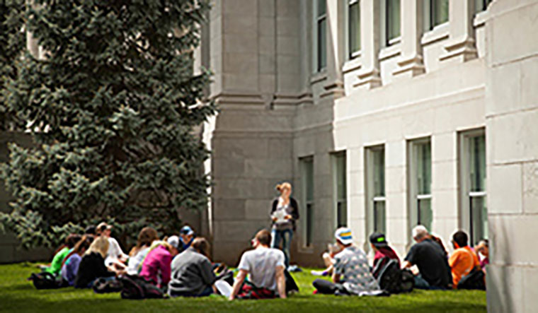 students in class sitting on grass outside of Siceluff Hall