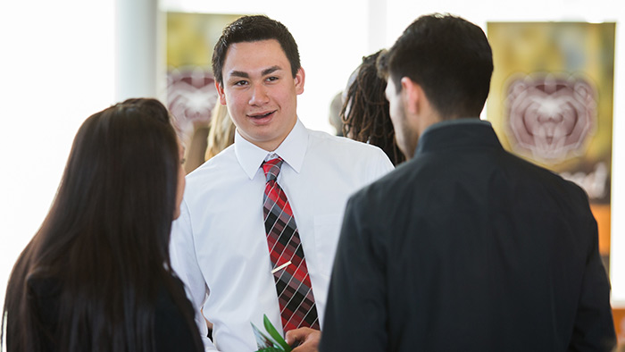 A student in business attires talks to others