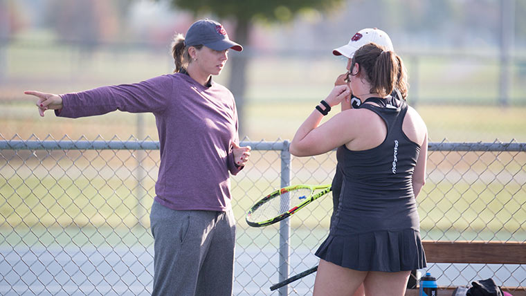 Tennis coach instructing player.