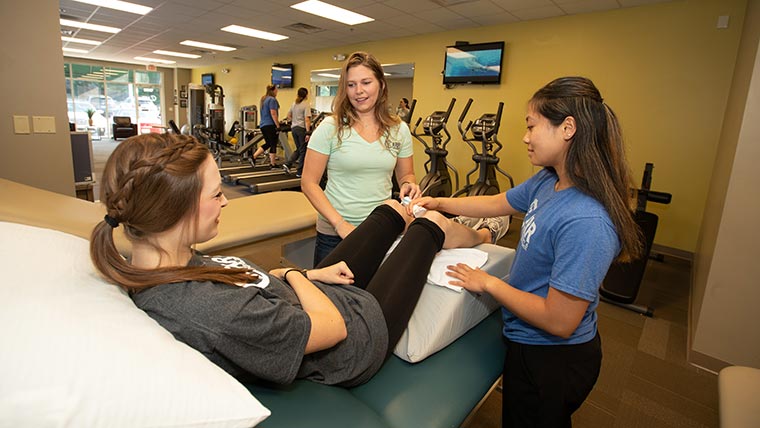Trainers helping patient through rehab exercise.