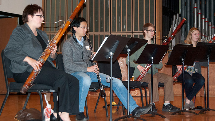 Three students sitting with instructor playing oboe and bassoon