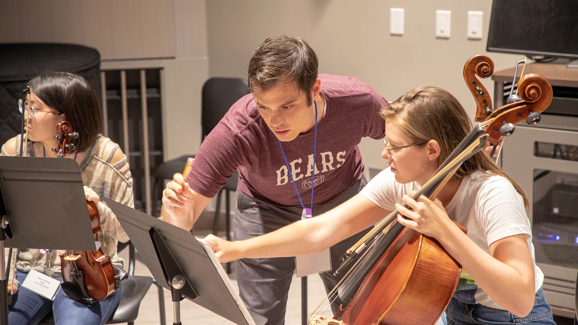 Dr. Daniel Ketter assists two String Fling students holding instruments