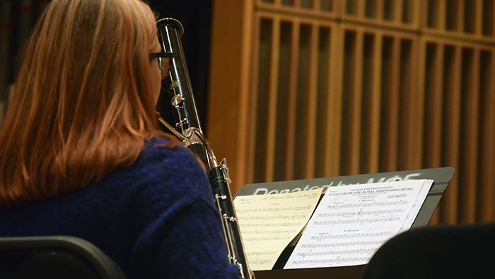 Student pictured playing oboe with sheet music visible