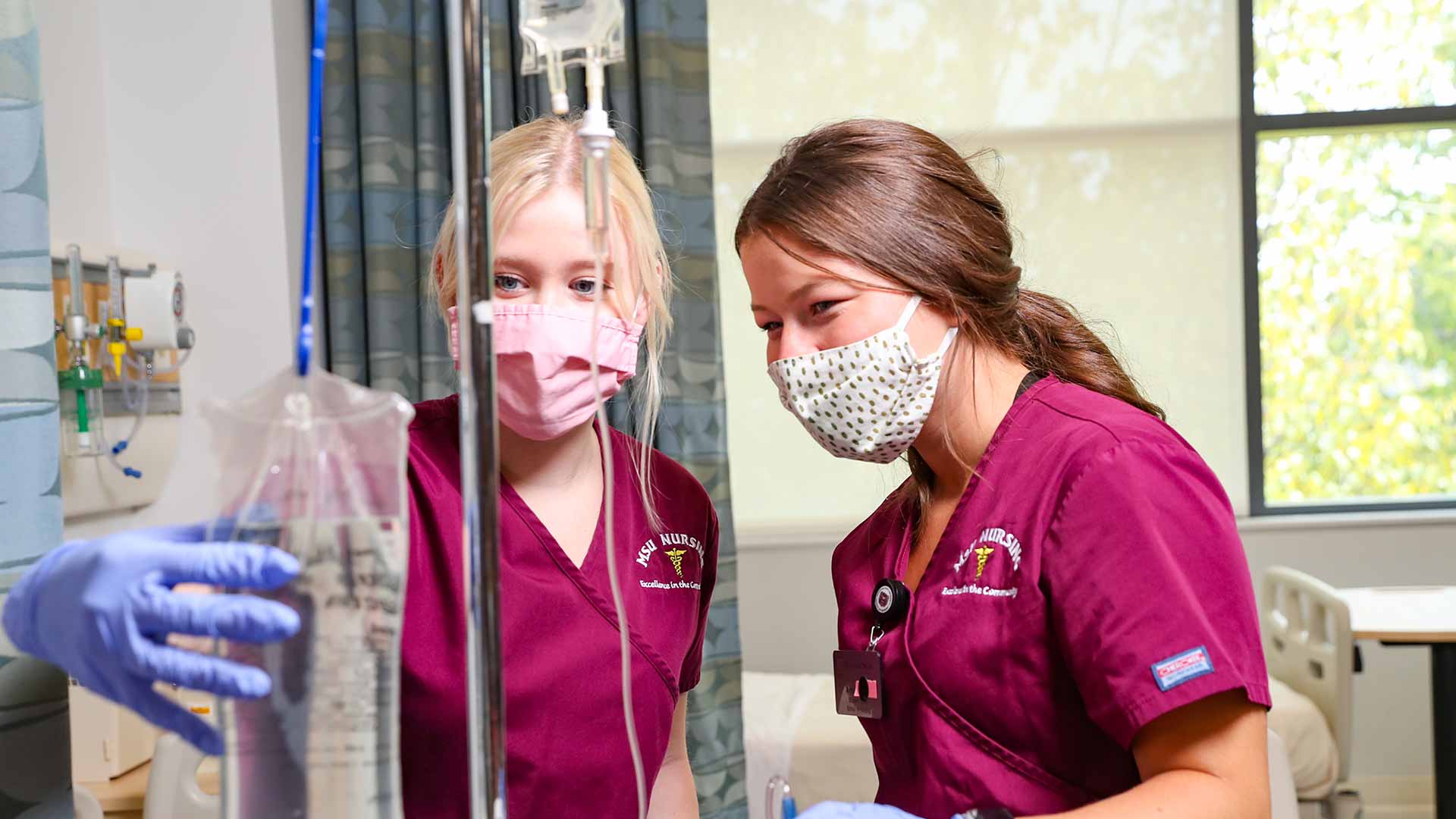 Nursing students checking IV bag in skills lab.