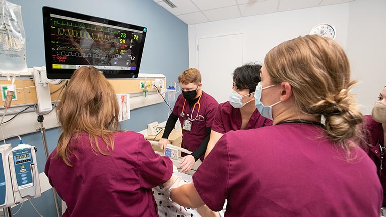 Nursing students checking vitals on simulation patient.