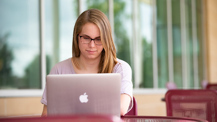 Nursing student typing on laptop.