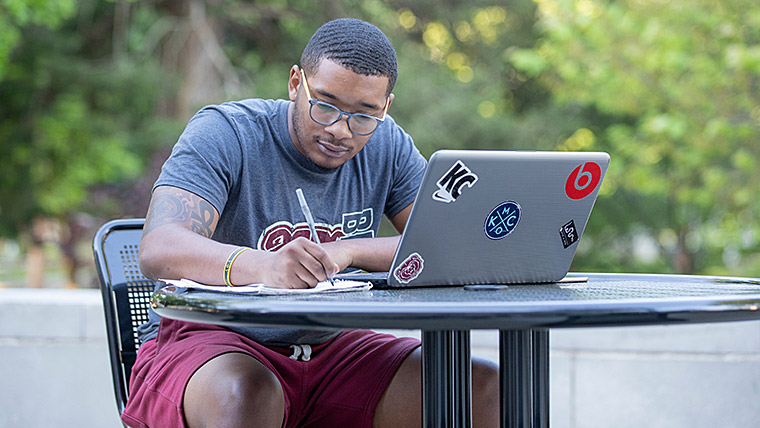MSU student studying outside with his laptop. 