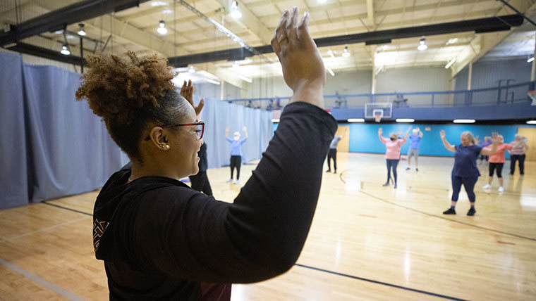 A gerontology students leads a group exercise class with older adults at the YMCA.