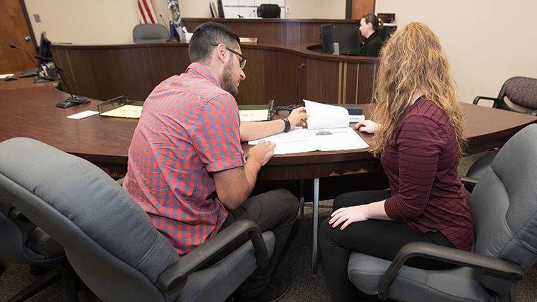 Two individuals looking over a case in a court room.