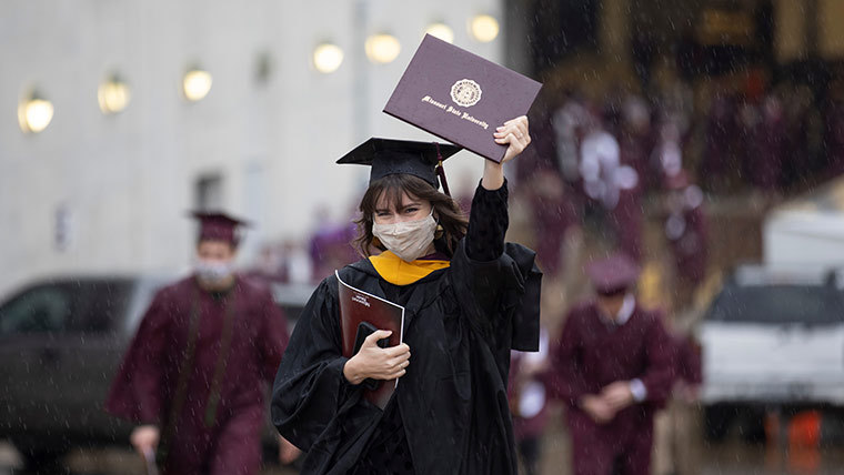 Student holding a diploma in her hand.