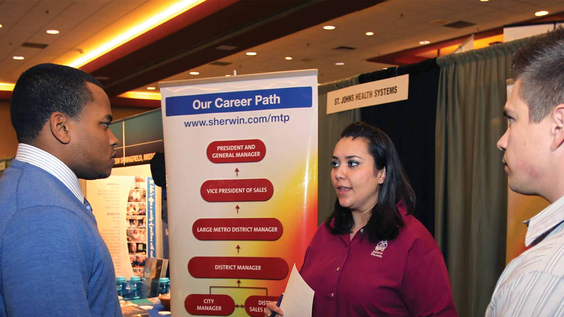Three people are talking at a career fair.