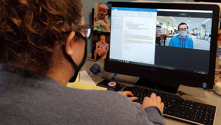 A student works on a computer; the computer's screen shows a word document and a video feed of a consultant