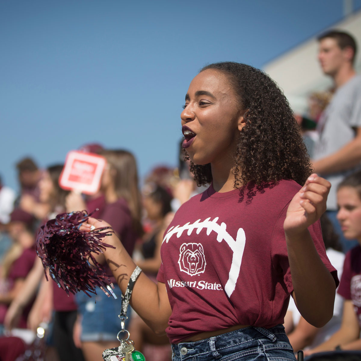 Female student cheers in student section of football stadium