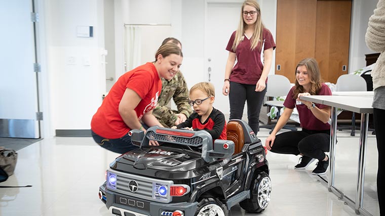OT students helping a child into adapted vehicle during class.