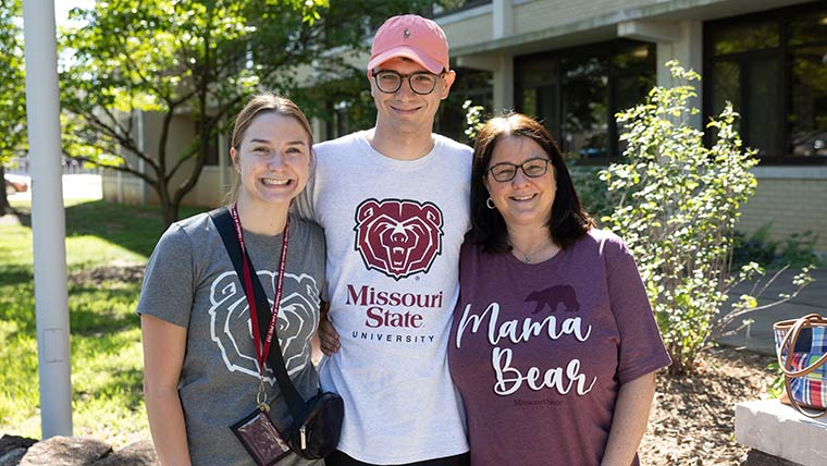 A Missouri State student with her family members outside of a residence hall on move-in weekend. All three are wearing BearWear.