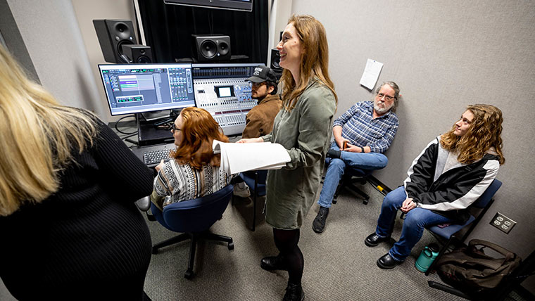 Cristina Pippa, assistant professor in the department of communication, media, journalism and film, works with a group of students in an audio production lab.
