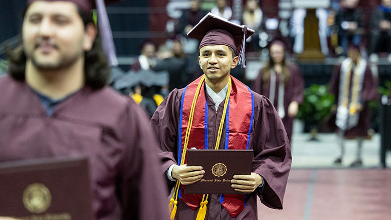A proud student walks with his diploma cover during commencement ceremonies.
