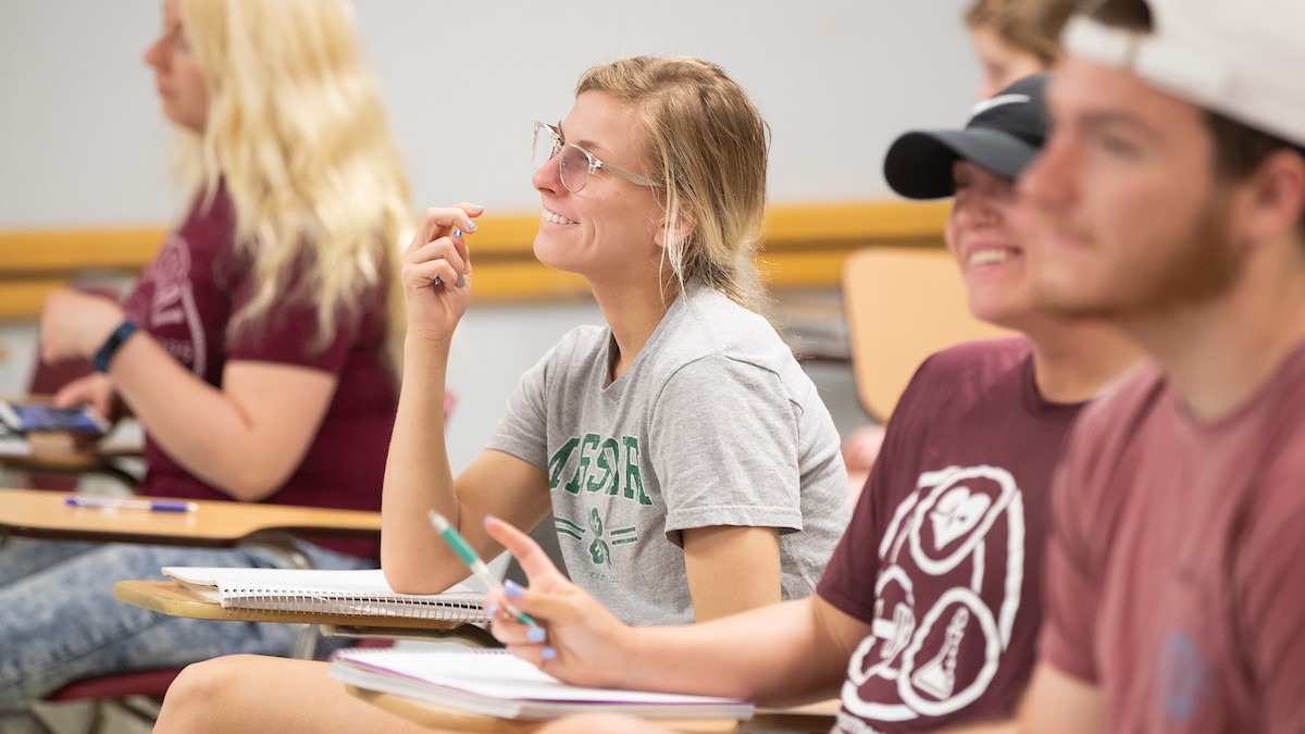 A student wearing a gray T-shirt enjoys a classroom lecture at Missouri State.
