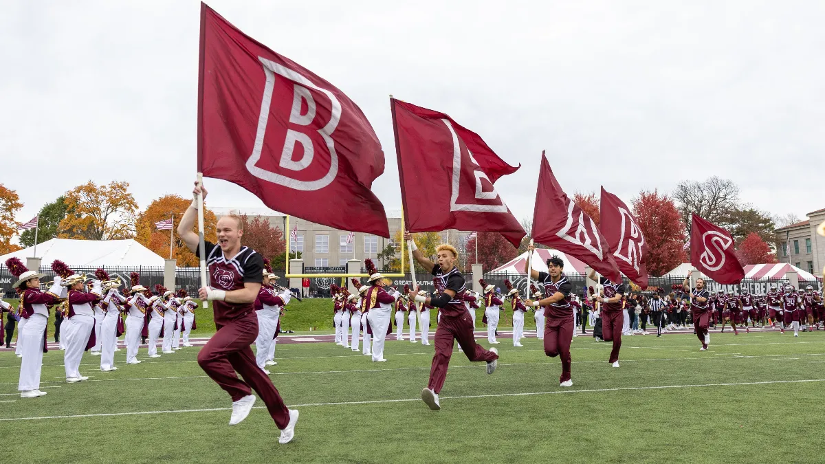 MSU cheerleaders carrying flags that spell out BEARS on the football field.