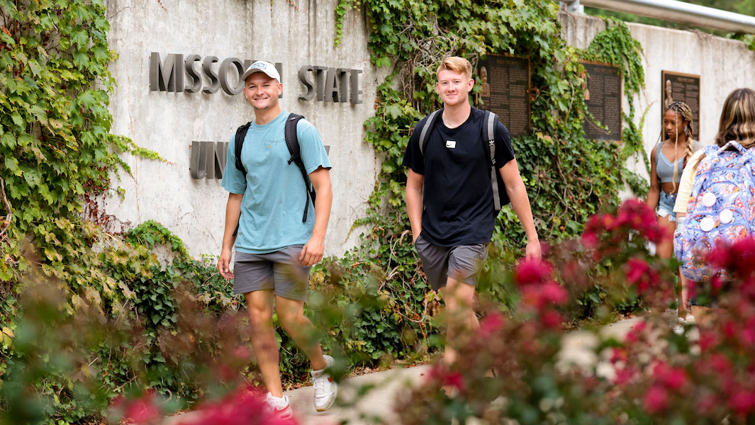 Missouri State students walking in front of the MSU memorial wall.