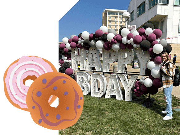 Kelly Sego standing next to a Happy BDay lighted display. A bagel graphic is also featured.