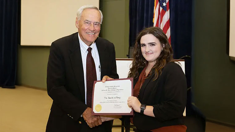 A faculty member presenting a scholarship award to a student