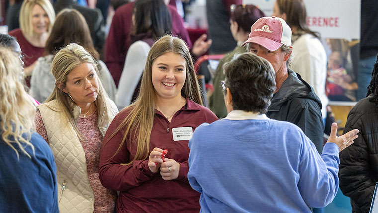 A visiting family speaking with an academic department representative.