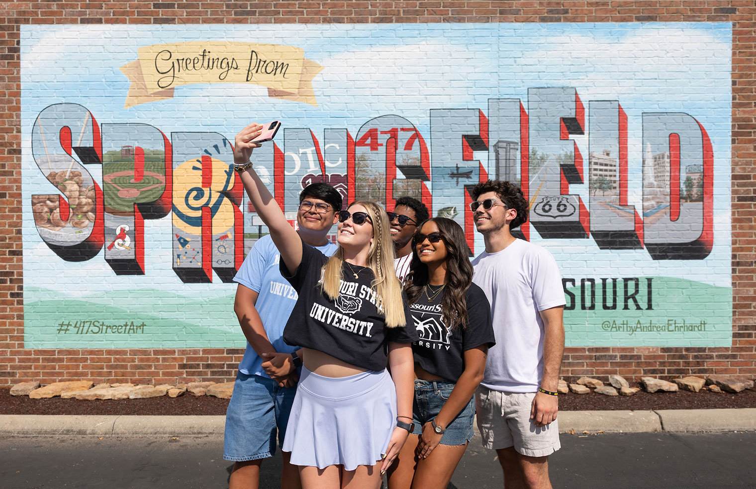 A group of five MSU students taking a group selfie in front of a Springfield mural