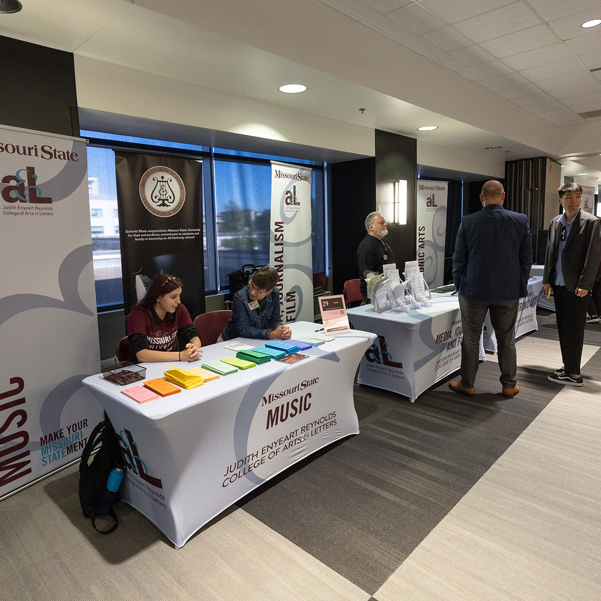 Two Missouri State employees are seated at a booth for the music department at the Majors Fair.
