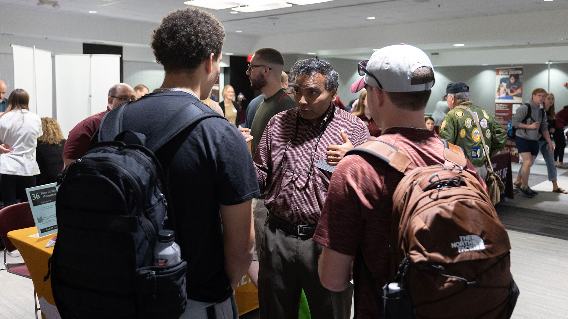 A faculty member share information about a program to two students during the Majors Fair.