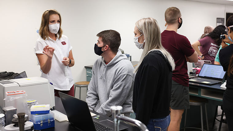Dr. Randi J. Ulbricht, an assistant professor in the biomedical sciences department, instructing two students during a lab class.