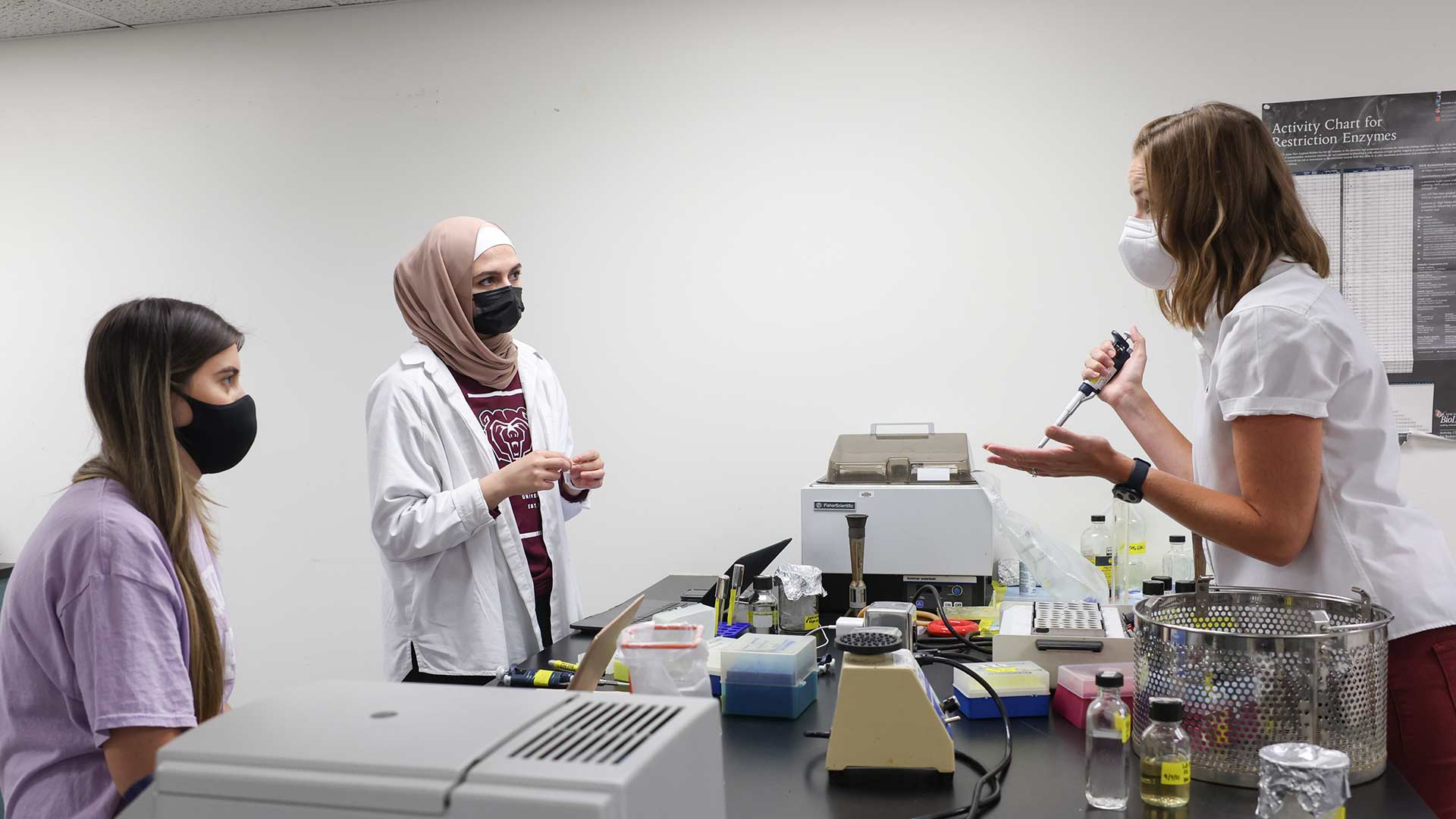 Professor instructing two students during a lab class.