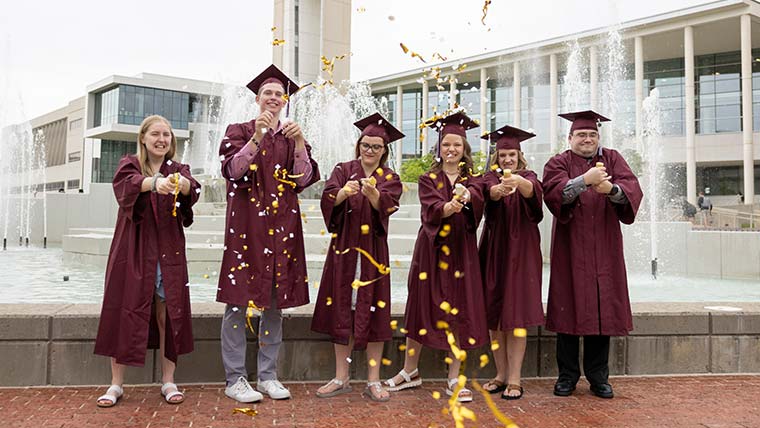 Bear POWER graduates, in cap and gowns, celebrating graduation day. 