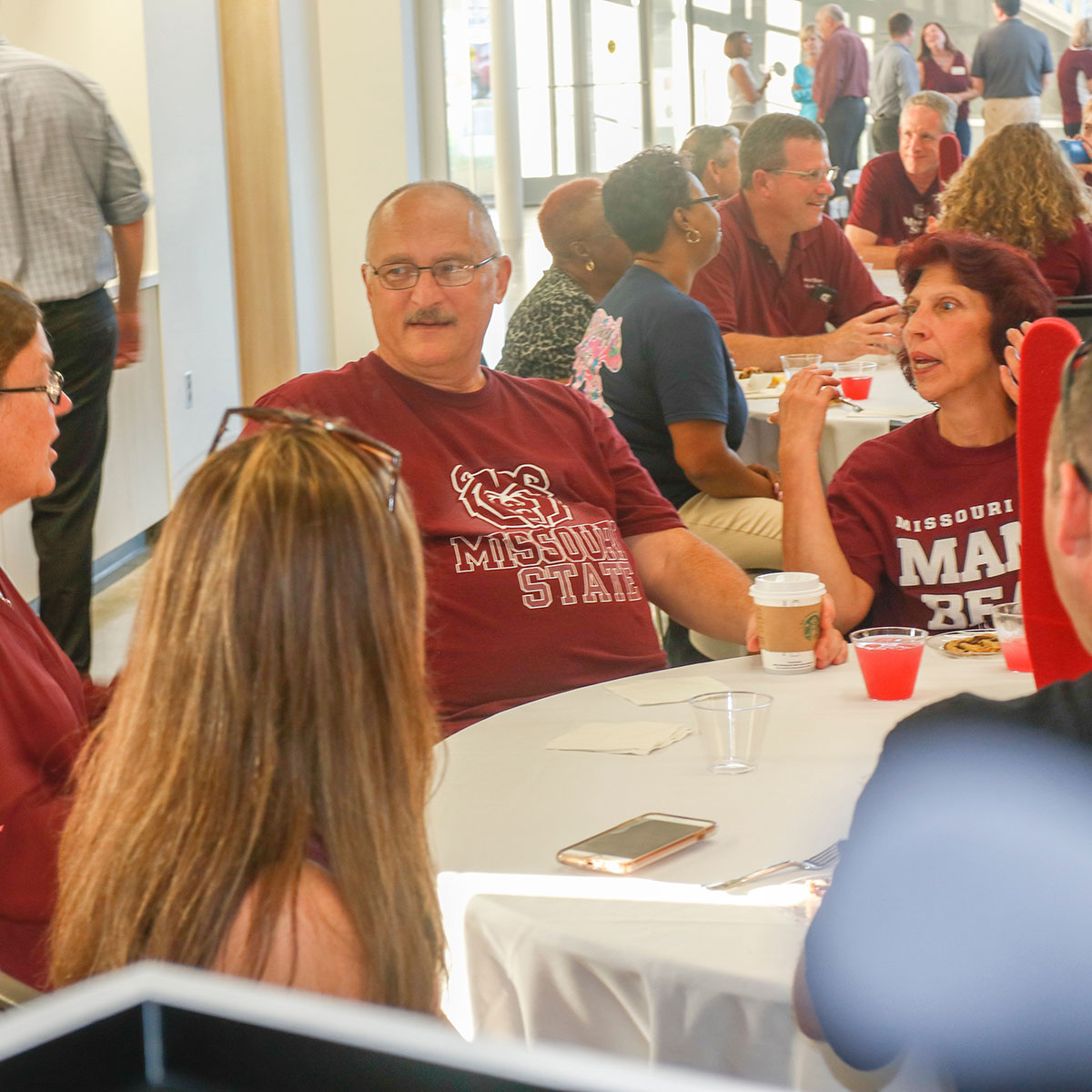 People eat and chat at tables in the Davis-Harrington Welcome Center during the President's Reception for New Families.