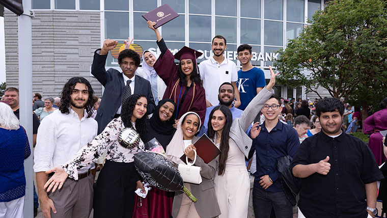 A student in her graduation cap and gown poses for a picture with her family after the commencement ceremony.