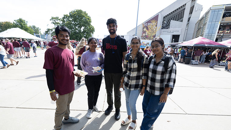 Five people enjoying food next to the MSU Football stadium during Family Weekend