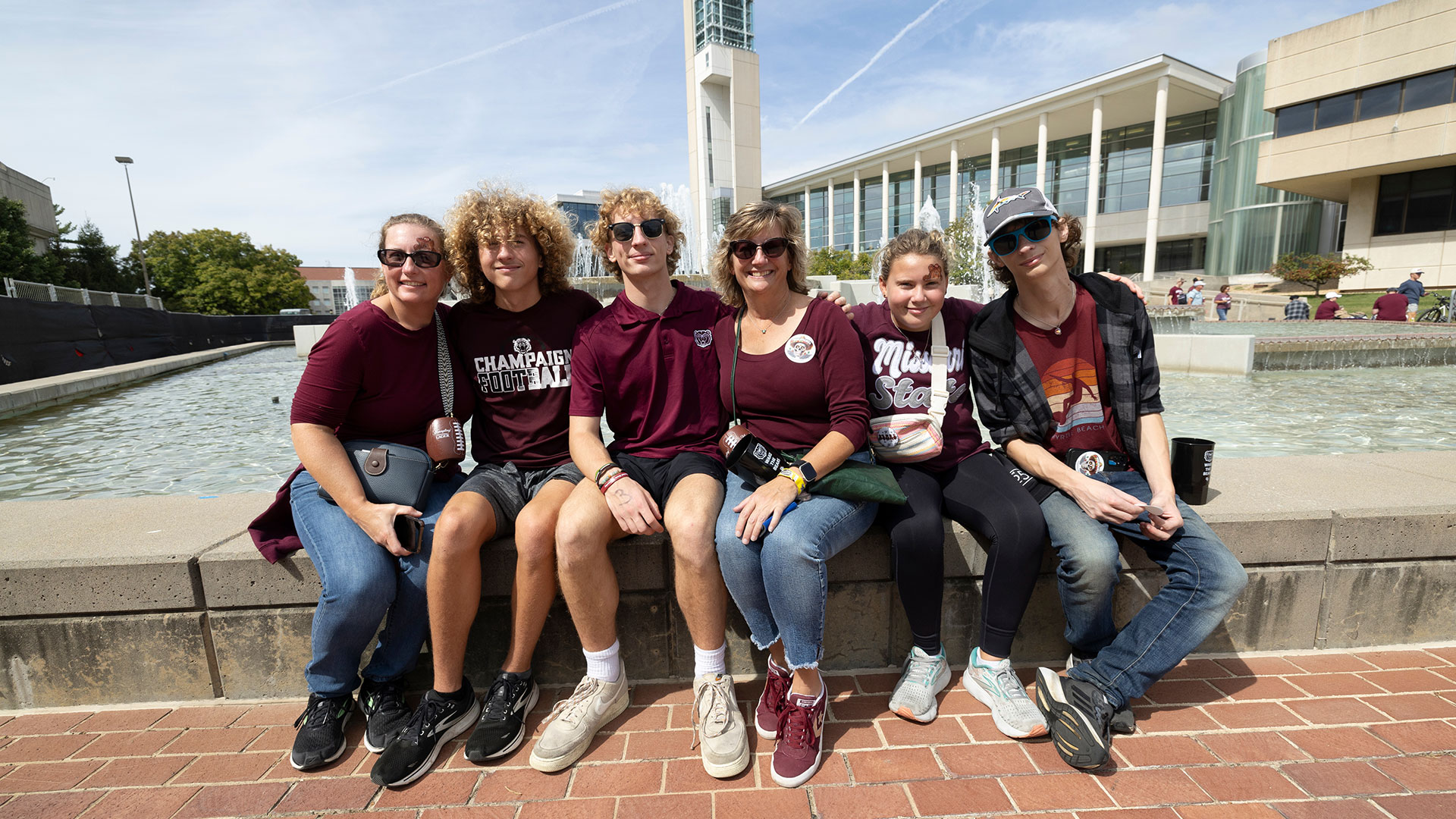 A family basks in the sun next to the MSU fountain on Family Weekend.