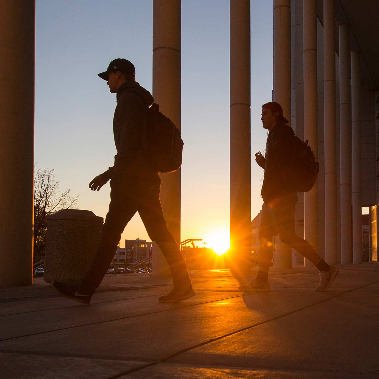 Two students walking out of Meyer Library at sunset.